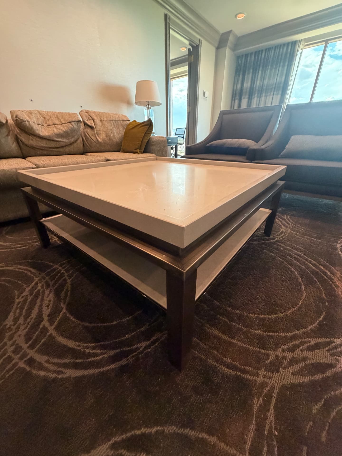 Suite living area with sofa, lounge chairs, table lamp and stone-top coffee table