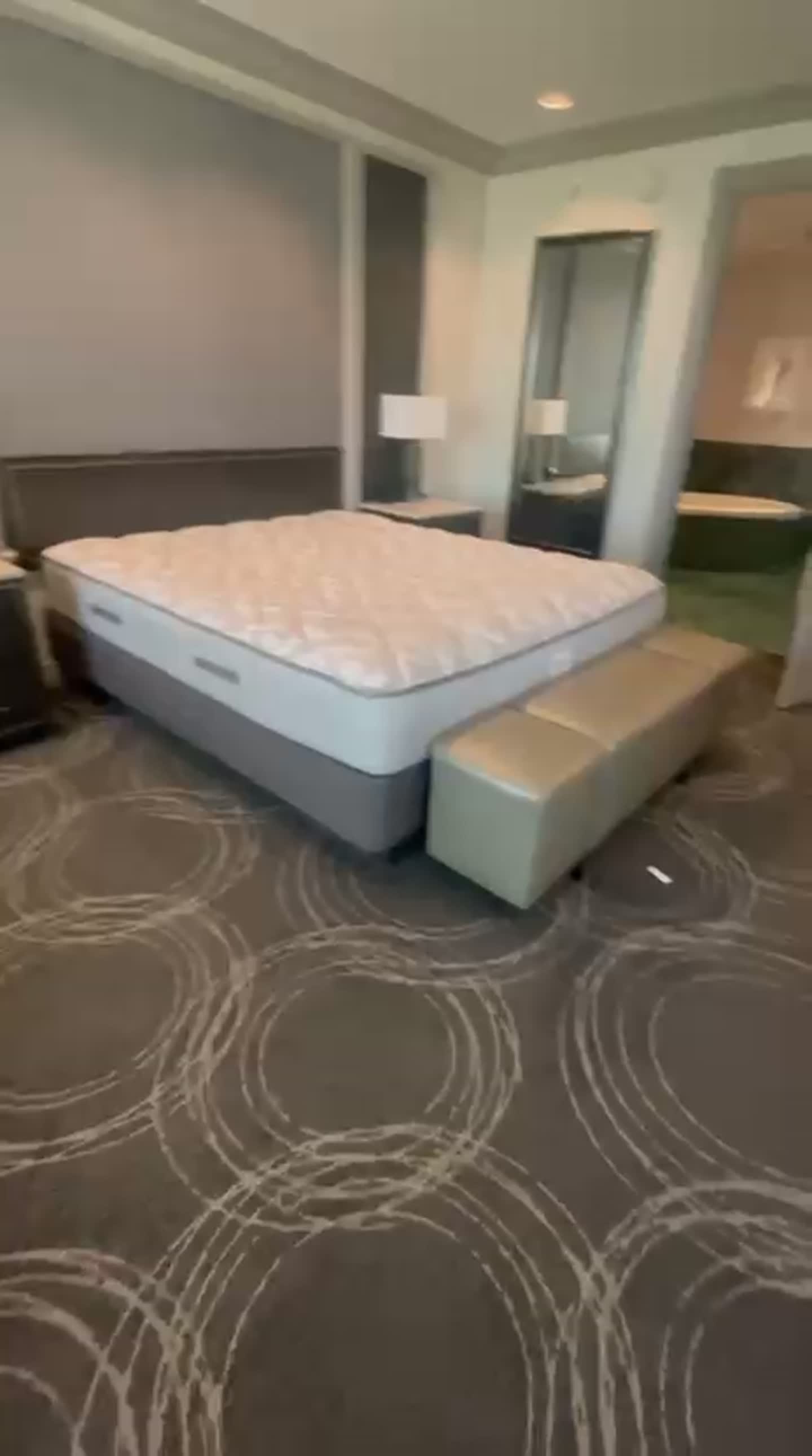 Suite bedroom with king bed, upholstered bench, nightstands, lamps and full-length mirror