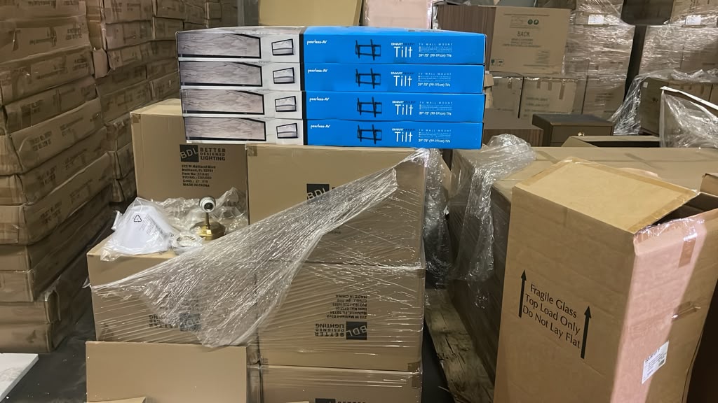 Boxed brand-new light fixtures and TV wall mounts on pallets
