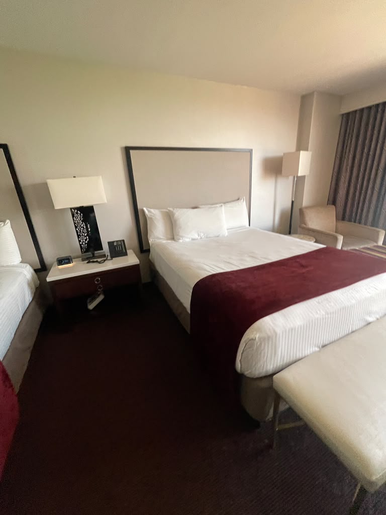 King bed with nightstand, table lamp, telephone, alarm clock and bench