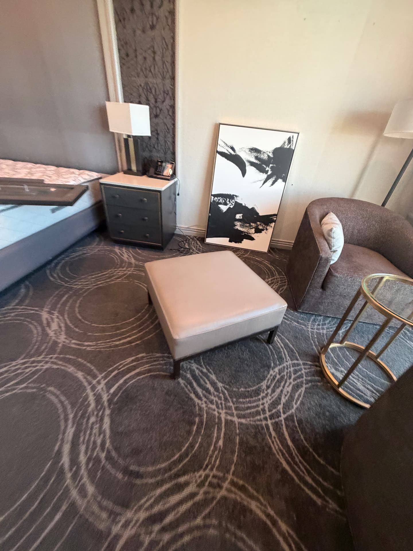 Suite seating corner with swivel lounge chair, leather ottoman, brass side table, floor lamp and framed art