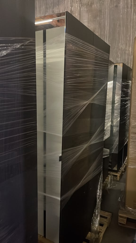 Row of brand-new wrapped wardrobe and mirror units on pallets